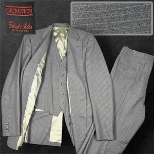 May include: A three-piece suit in light gray with a subtle pinstripe pattern, featuring a jacket, a five-button vest, and trousers. The jacket has a light-colored lining and the label reads CRICKETEER Frederick & Nelson Store for Men.