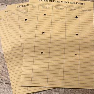 May include: A stack of four brown paper forms with holes punched in the top left corner. The forms are labeled "Inter-Department Delivery" and have columns for "Date", "Deliver To", "Department", "Sent By", and "Department".