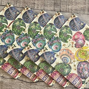 May include: Set of six cream-colored fabric napkins with a colorful Easter egg design. The eggs are decorated with intricate patterns and colors, including blue, green, red, and gold.