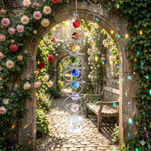 May include: A decorative wind chime with a spiral design and colorful crystal beads. The wind chime features a rainbow of colors, including red, orange, yellow, green, blue, and purple, and a large clear crystal at the bottom. The wind chime hangs from a silver chain.