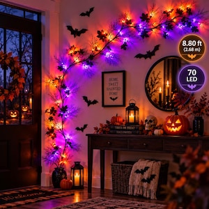 May include: An 8.80 ft (2.68 m) Halloween garland featuring 70 LED lights, black branches, and autumn-colored leaves. The garland is adorned with black bat cutouts and is displayed alongside a jack-o'-lantern, a lantern, and a skull decoration.
