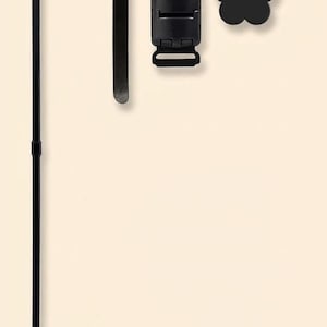 May include: Black metal garden flag holder with a curved top and a hook. Includes a black clip, a strap, and a flower-shaped accent. The stand is designed to hold a garden flag and is suitable for outdoor use.