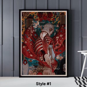 May include: Framed art print featuring a stylized illustration of Frankenstein. The artwork has a dark color palette with red, white, and blue accents. The print includes the title "Frankenstein" and the name "Guillermo del Toro" in white text. Style #1 is printed at the bottom.