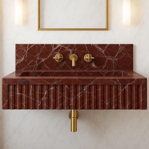 Luxury 26-inch wall-mounted sink made from Rosso Levanto marble with fluted front and integrated backsplash.