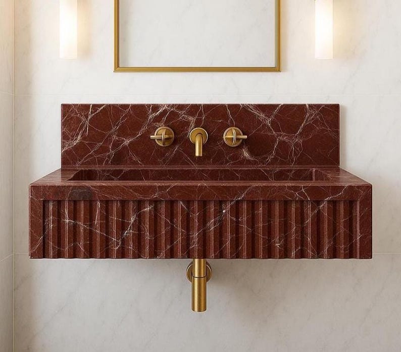 Luxury 26-inch wall-mounted sink made from Rosso Levanto marble with fluted front and integrated backsplash.