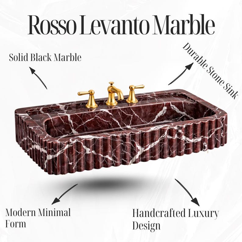 May include: A rectangular Rosso Levanto marble sink with fluted sides and gold-coloured taps. The durable stone sink has a modern, minimal form and handcrafted luxury design. The text "Rosso Levanto Marble" is at the top. The sink is made of solid black marble.