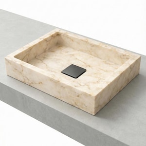 Peut inclure: Un évier rectangulaire en marbre avec un drain carré noir. L'évier est de couleur beige clair avec des veines marron. L'évier est posé sur une surface grise.