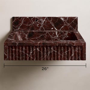 Artisan-crafted fluted marble sink in Rosso Levanto stone, showcasing natural white veins and deep red color.