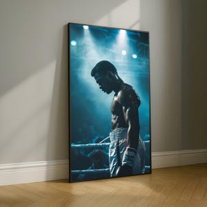 Può includere: Stampa incorniciata di un pugile sul ring, illuminata da riflettori. Il pugile indossa pantaloncini e guantoni bianchi, con un'espressione concentrata. Lo sfondo è una folla sfocata, con uno schema di colori blu e bianco.