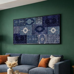 May include: A framed wall art piece featuring a patchwork design of various blue and white patterned rug sections. The artwork is rectangular and hangs on a dark green wall above a blue sofa with orange and cream-colored throw pillows.
