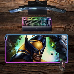 Könnte beinhalten: Ein Gaming-Setup mit einem gebogenen Monitor, einer Tastatur mit Hintergrundbeleuchtung und einem großen Mauspad mit Wolverine-Grafik. Eine passende Gaming-Maus ist ebenfalls vorhanden. Die Artikel sind auf einer Holzoberfläche angeordnet.