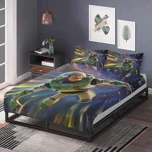Puede incluir: Juego de cama con Buzz Lightyear. La funda n&oacute;rdica y las fundas de almohada muestran una imagen din&aacute;mica de Buzz Lightyear en vuelo, sobre un fondo de estrellas y rayos de luz. La cama tiene un marco negro y la habitaci&oacute;n incluye obras de arte enmarcadas.