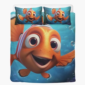 May include: Bedding set featuring a large, smiling orange clownfish with white stripes and large eyes. Two matching pillowcases with the same fish design are visible against a blue underwater background. The bedding set is designed for a child's bedroom.