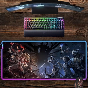 May include: Gaming setup featuring a curved monitor, a backlit keyboard, and a mouse. The mousepad displays a fantasy battle scene with warriors and a dark tree. The keyboard has multi-colored keys, and the mouse has a red and black design.