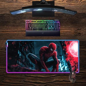 May include: A gaming setup featuring a curved monitor, a backlit keyboard, and a mouse pad with a Spider-Man graphic. A matching mouse is also visible. The keyboard has a rainbow color scheme.