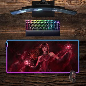 May include: A gaming setup featuring a curved monitor, a backlit keyboard, and a large mousepad with a red and purple graphic of a character. A matching mouse is also present. The keyboard has rainbow lighting.
