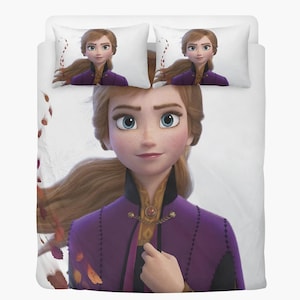 Könnte beinhalten: Ein weißes Bettwäsche-Set mit einem großen Bild einer Zeichentrickfigur mit langen braunen Haaren, blauen Augen und einem lila-schwarzen Outfit. Zwei passende Kissenbezüge mit derselben Figur sind sichtbar.