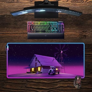 May include: A gaming setup featuring a curved monitor, a backlit keyboard, and a mouse. The mousepad displays a cartoon scene of a house, windmill, and car under a starry sky, with a purple and pink border. The keyboard has rainbow-colored keys.