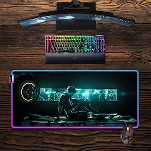 Può includere: Un setup da gaming con un monitor curvo, una tastiera con illuminazione arcobaleno e un ampio tappetino per mouse con un'illustrazione futuristica. È presente anche un mouse da gaming abbinato. Il setup è su una superficie di legno.