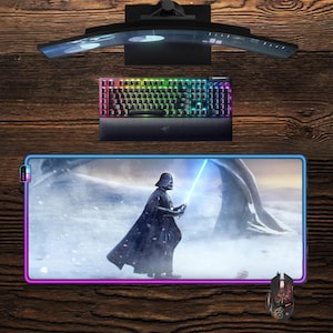 Könnte beinhalten: Ein Gaming-Setup mit einem gebogenen Monitor, einer Tastatur mit Regenbogenbeleuchtung und einer Maus. Das Mauspad zeigt Darth Vader mit einem Lichtschwert. Das Setup befindet sich auf einer Holzoberfläche.