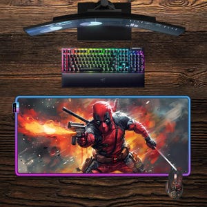 May include: A gaming setup featuring a curved monitor, a backlit keyboard, and a Deadpool-themed mousepad with a matching mouse. The mousepad has a colorful border and a graphic of Deadpool holding a gun.