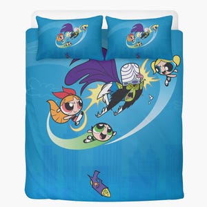 Op de afbeelding: Blauwe Powerpuff Girls beddengoedset met Blossom, Bubbles en Buttercup die vechten tegen Mojo Jojo. De set bevat een dekbedovertrek en twee kussenslopen. De stripfiguren staan tegen een blauwe achtergrond met stads silhouetten.