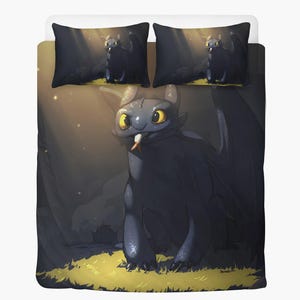 May include: A bedding set featuring a cartoon dragon with large yellow eyes and a white tongue. The dragon is black with large wings, set against a forest background with light rays. The set includes two pillowcases and a duvet cover.
