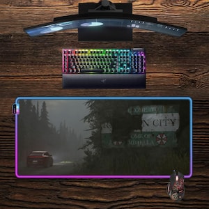 May include: A gaming setup featuring a curved monitor, a backlit keyboard, a mouse, and a large mousepad with a colorful border. The mousepad displays a scene with a road sign that reads "N City".
