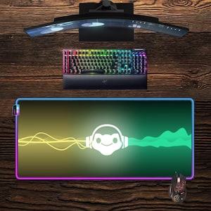 Peut inclure: Configuration de jeu avec un écran incurvé, un clavier rétroéclairé et un grand tapis de souris avec un design coloré. Le tapis de souris présente un graphisme blanc et un dégradé violet, jaune et vert. Une souris de jeu est également visible.