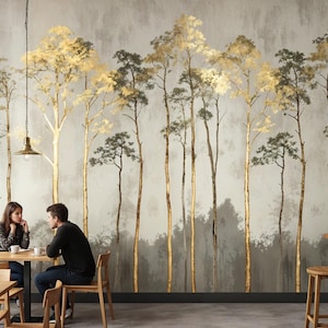 May include: A cafe interior featuring a mural of stylized trees with gold and green foliage against a gray backdrop. Two people sit at a table, and the cafe has wooden tables, chairs, and stools. Overhead, there are pendant lights.