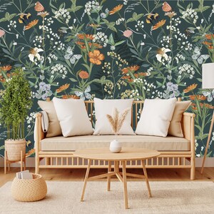 May include: A living room scene featuring a floral wallpaper with butterflies, flowers, and foliage in shades of green, orange, and white. A light-colored wooden sofa with white pillows, a round coffee table, and a floor lamp complete the decor.