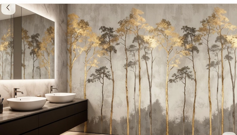 May include: A bathroom with a modern design featuring a wall mural of stylized trees. The trees have gold and gray foliage and trunks against a muted gray background. The bathroom includes a dark brown vanity with two white vessel sinks and a large mirror.