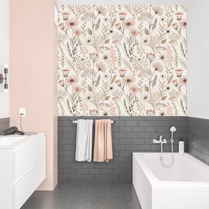 May include: A bathroom with a white bathtub, sink, and floral wallpaper. The wallpaper features a repeating pattern of beige, pink, and brown flowers and foliage. The walls are painted in white and pink, with dark gray tile accents.