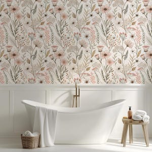 May include: A bathroom scene featuring a white, freestanding bathtub with a white towel draped over the side. The wall behind the tub is covered in floral wallpaper with pink, white, and green botanical elements. A small wooden stool holds towels and a soap dispenser.