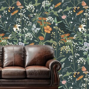 May include: A dark green floral wallpaper featuring orange, white, and yellow flowers, butterflies, and bees. A brown leather sofa is in the foreground. The wallpaper has a botanical theme.