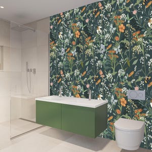 May include: A modern bathroom with a green vanity, white sink, and toilet. The wall features a dark green floral wallpaper with orange, white, and purple flowers. A glass shower enclosure is on the left.