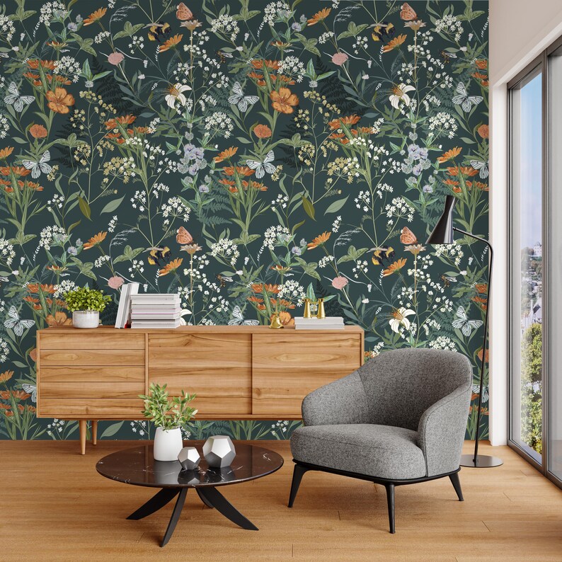 May include: A dark green floral wallpaper featuring a pattern of white, orange, and purple flowers, along with butterflies. The wallpaper is the backdrop for a wooden cabinet, a gray armchair, and a black coffee table.