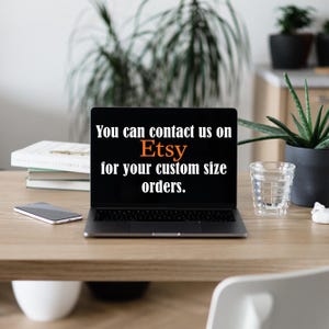 May include: A laptop displaying the Etsy logo and the text "You can contact us on Etsy for your custom size orders." The laptop is on a wooden desk with a smartphone, books, and a glass of water.