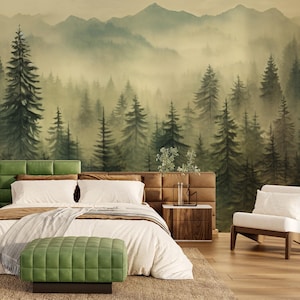 Könnte beinhalten: Schlafzimmer-Interieur mit einem Wald-Wandbild, einem grün gepolsterten Kopfteil und einer passenden Ottomane. Das Bett hat weiße Bettwäsche und einen hellfarbigen Überwurf. Ein Nachttisch aus Holz und ein weißer Sessel vervollständigen die Szene.