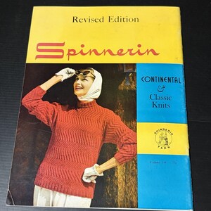 以下が含まれることがあります： 「Revised Edition Continental & Classic Knits Volume 144」と題されたSpinnerinのヴィンテージ編み物パターンブックレット。表紙には、赤い質感のある長袖セーター、白いヘッドスカーフ、白い手袋を着用した人物が暗い背景を背にして写っています。