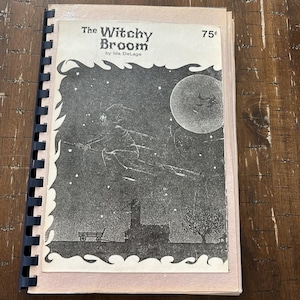 Può includere: Un libro con rilegatura a spirale intitolato The Witchy Broom di Ida DeLage, al prezzo di 75 centesimi. La copertina presenta un'illustrazione in bianco e nero di una figura che vola su una scopa contro un cielo notturno con una grande luna, stelle, una casa e un carro.