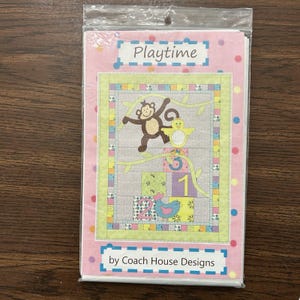 May include: A packaged quilt pattern titled "Playtime" featuring a colorful design with a monkey, bird, and numbers. The pattern includes the text "by Coach House Designs" on a pink background with polka dots.