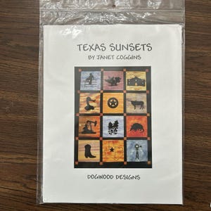 May include: A packaged craft pattern titled "Texas Sunsets" by Janet Coggins. The pattern features a grid of colorful squares with Texas-themed silhouettes, including a cowboy, longhorn, and oil derrick. The bottom of the pattern reads "DOGWOOD DESIGNS."