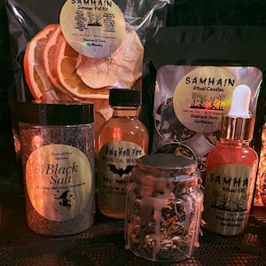May include: A collection of apothecary items including a Samhain simmer pot kit with dried fruit, a jar of black salt, a bottle of Holy Hell Fire Florida Water, a bag of Samhain ritual candles, a small jar with wax drippings, and Samhain ritual oil.