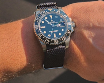 May include: A stainless steel wristwatch with a blue dial and a black nylon strap. The watch has a rotating bezel with blue and black sections and luminous hands and markers. The watch is on a wrist.