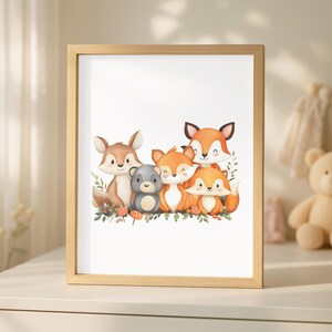 Op de afbeelding: Een ingelijste print met een aquarel illustratie van een familie van vossen en een berenjong. De vossen zijn oranje en bruin, de beer is grijs. Het kunstwerk staat tegen een witte achtergrond, met groen en paddenstoelen aan de onderkant.