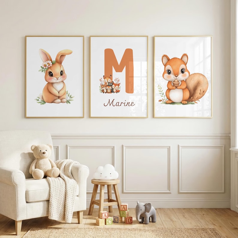 Op de afbeelding: Drie ingelijste kunstprints met bosdieren. E&eacute;n print toont een konijn met een bloemenkrans, een andere de letter "M" met "Marine" eronder, en de derde een eekhoorn met een eikel. De prints hebben gouden lijsten.