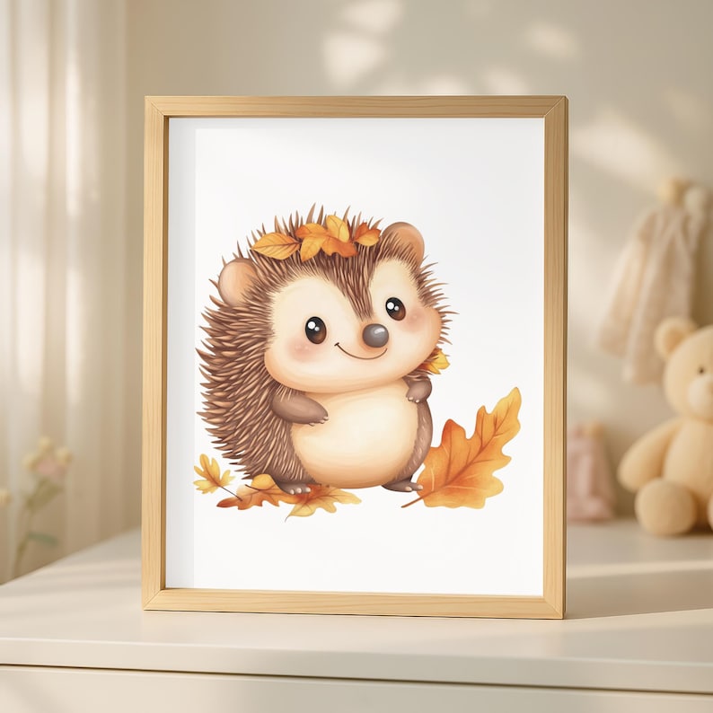 Op de afbeelding: Een ingelijste print met een aquarel illustratie van een egel. De egel heeft bruine stekels en een lichtbruin lichaam, versierd met herfstbladeren. Het kunstwerk staat tegen een witte achtergrond, ingelijst in een licht houten frame.