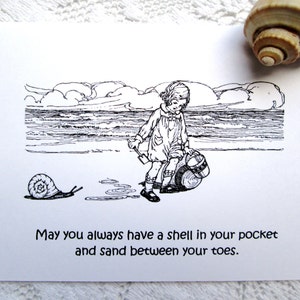 May include: Black and white illustration of a girl on a beach with a bucket and shovel. A snail is in the sand. The text reads "May you always have a shell in your pocket and sand between your toes."