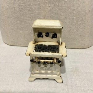 Estufa de juguete antigua en miniatura de hierro fundido pintado de blanco.